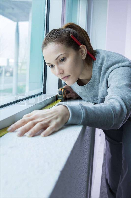 Woman measuring under window, stock photo