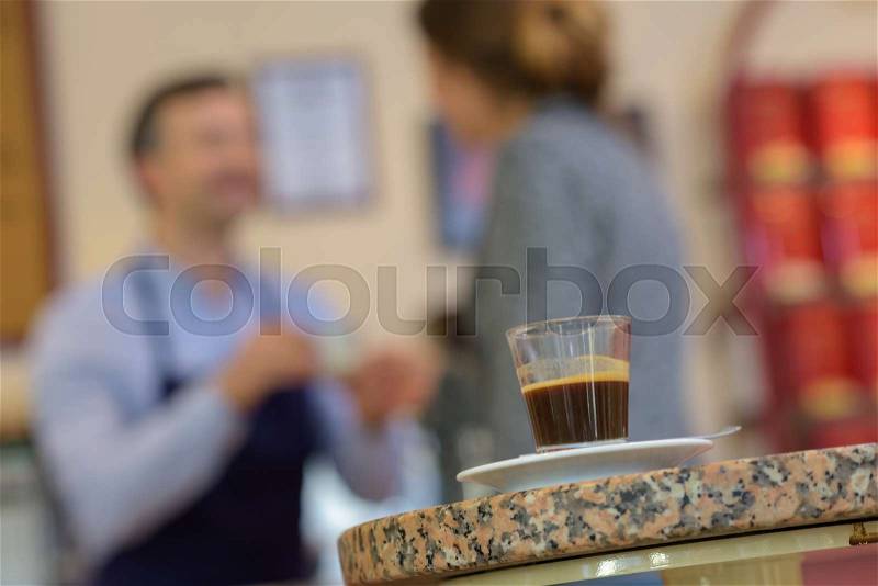 Espresso coffee in foreground, people behind, stock photo