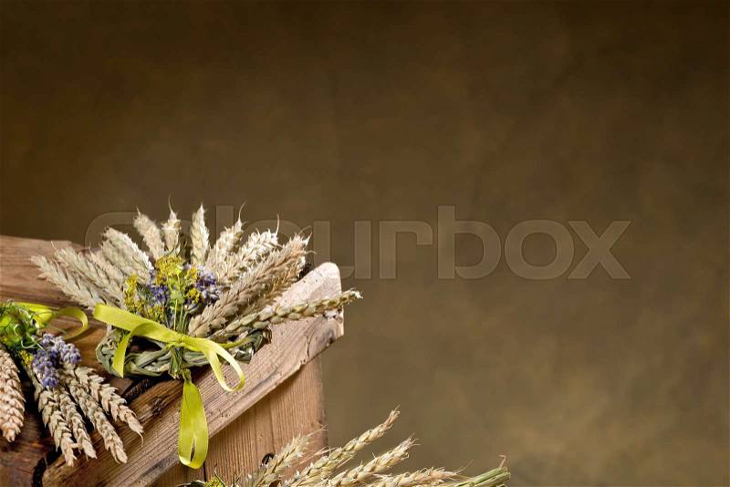 Bundle of wheat with flower and band on the brownd background, stock photo