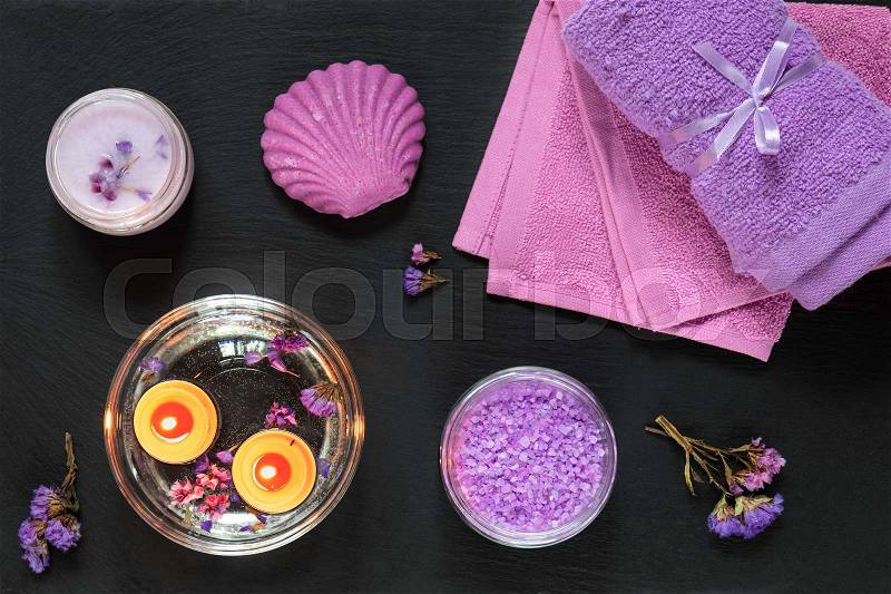 Spa products. Lavender bath salts, dry flowers, soap, cosmetic cream, candles and towel. Violet purple concept. Flat lay on black background, top view, stock photo