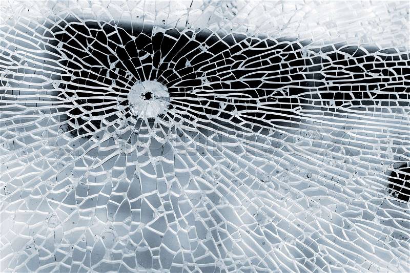 Broken strained glass with bullet hole and craks. Close-up background photo texture, stock photo