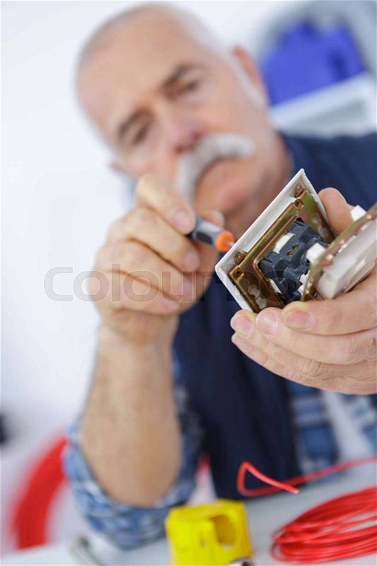 Senior male tech tests electronic equipment in service centre, stock photo