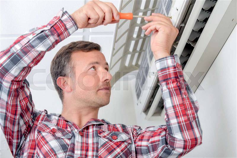 Man repairing air conditioning unit, stock photo