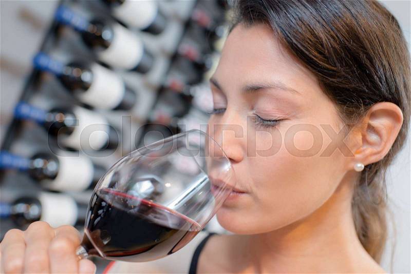 Lady drinking glass of red wine, eyes closed, stock photo
