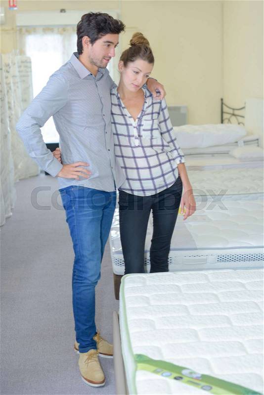 Couple choosing bed in a furniture shop, stock photo