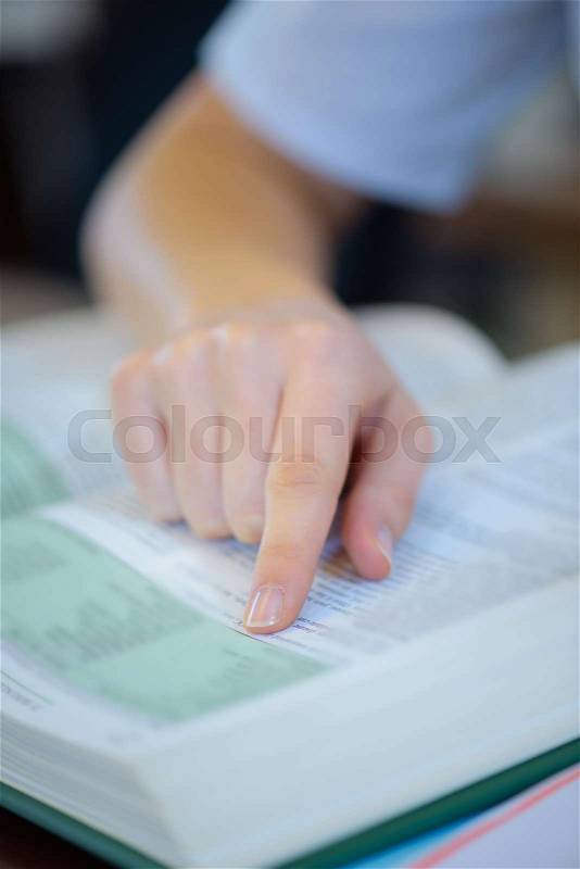 Closeup of index finger on text of book, stock photo