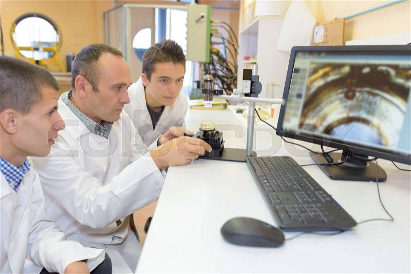 Students magnifying image onto computer screen, stock photo
