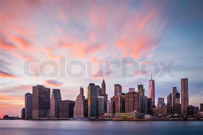 View of the New York Lower Manhattan buildings with colorful clouds above, stock photo