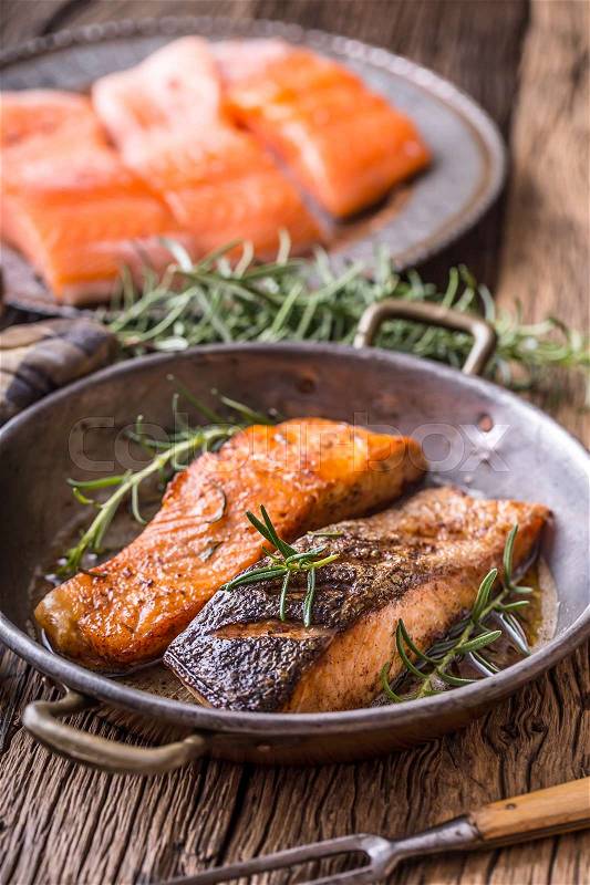 Salmon fillets. Grilled salmon, sesame seeds herb decorationon on vintage pan or black slate board. fish roasted on an old wooden table.Studio shot, stock photo