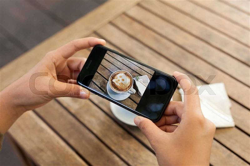 Close-up hand holding phone mobile taking photo coffee on table, stock photo
