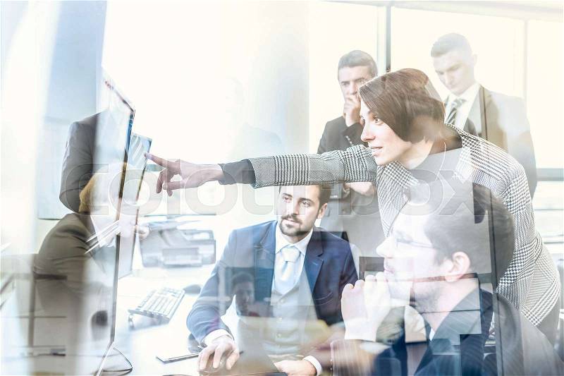 Business team looking at data on multiple computer screens in corporate office. Businesswoman pointing on screen. Business people trading online. Business, entrepreneurship and team work concept, stock photo