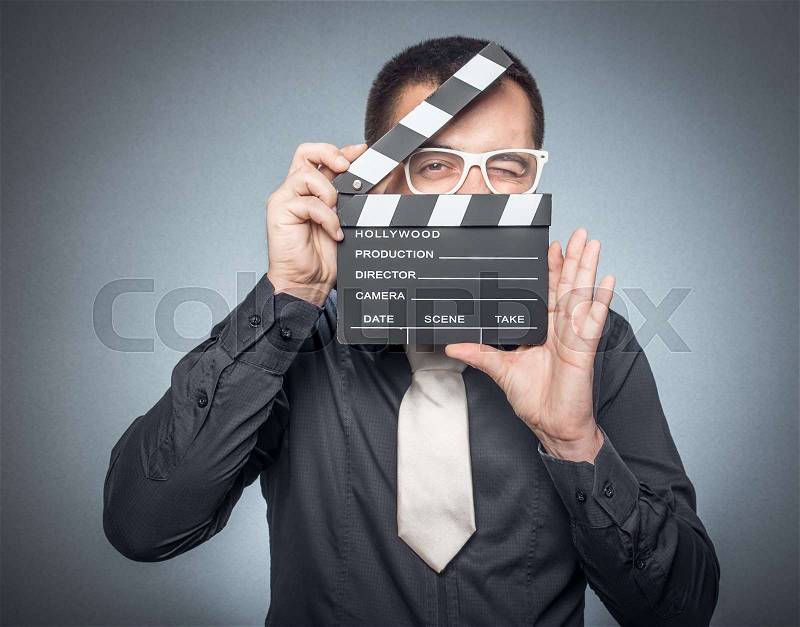 Man holding movie clapper board, isolated on gray background, studio shot. Film director, stock photo