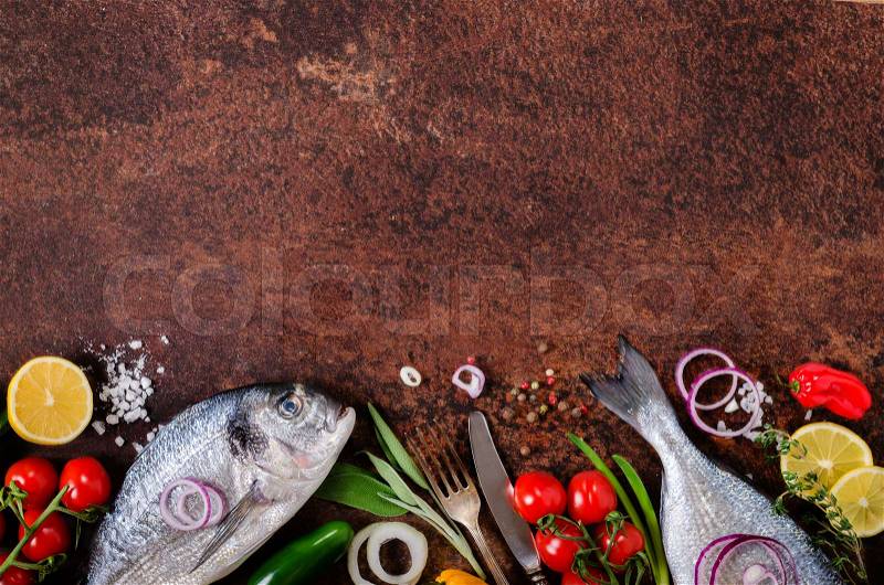 Fresh raw fish with lemon, herbs, onion, paprika, cherry tomatoes, onion, salt on rustic background. Healthy food concept. Free space for your text, stock photo