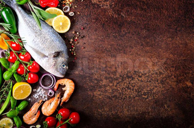 Fresh fish, shrimps with herbs, spices and vegetables on dark vintage background. Healthy food, diet or cooking concept. Free space for your background, stock photo
