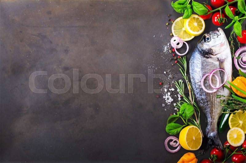 Fresh uncooked fish, dorado, sea bream with lemon, herbs, vegetables and spices on rustic background. Top view. Free space for your text, stock photo