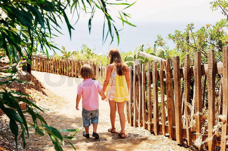 Two kids walking dowm the small path, back view, image taken in Capo Vaticano, Calabria, Italy, stock photo