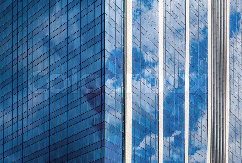 Modern smoked glass office building against a blue cloudy sky, stock photo