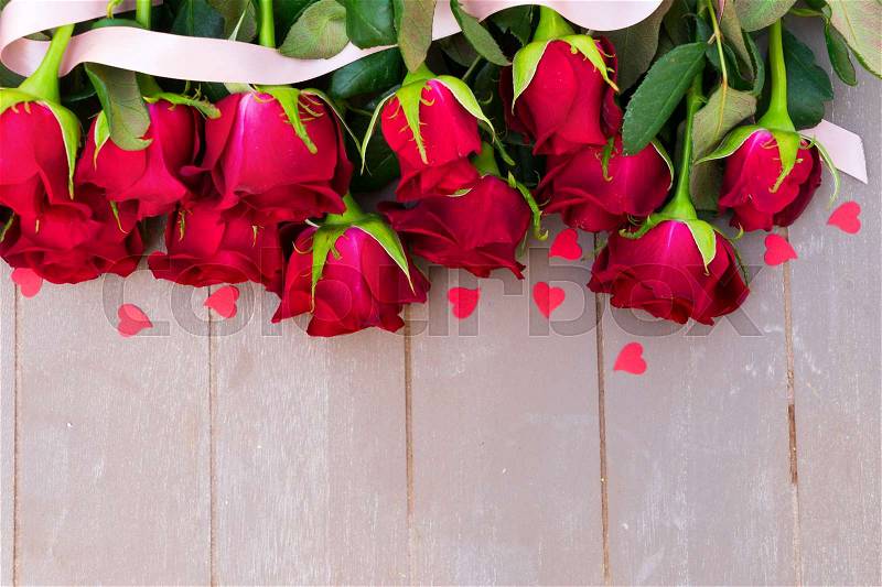 Dark Red buds of valentines day roses flowers border on wood with ribbon and hearts, stock photo