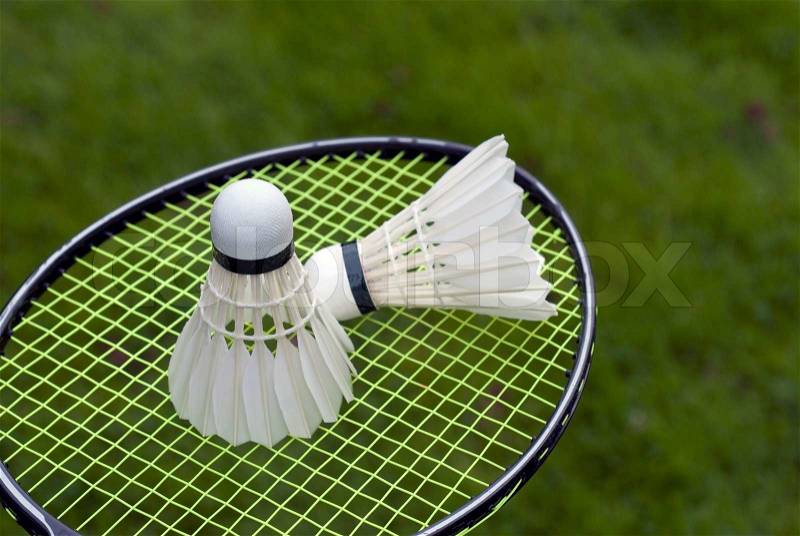 Two shuttlecocks on racket outdoors on green grass just before badminton play, stock photo