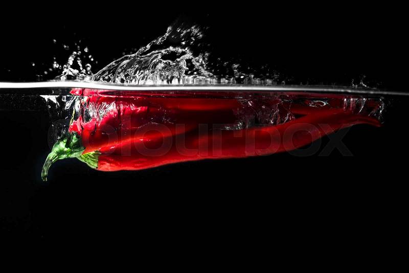 Red chili peppers falling into the water isolated on the black background, stock photo