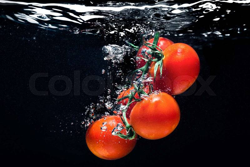 High speed photography tomato splash in water isolated on the black background, stock photo