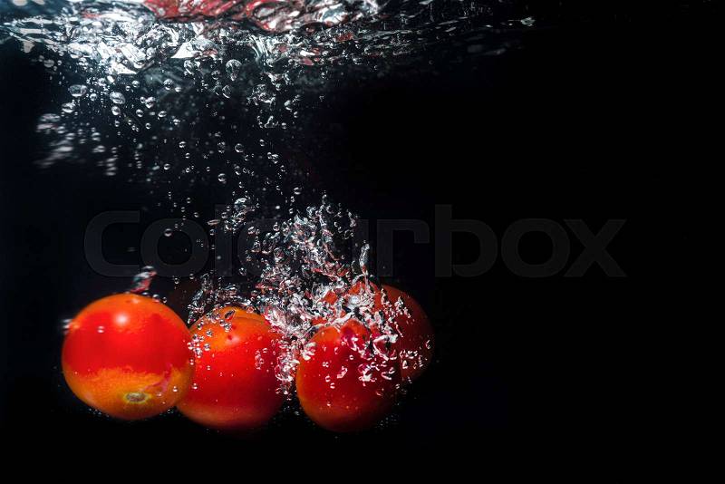 High speed photography tomato splash in water isolated on the black background, stock photo