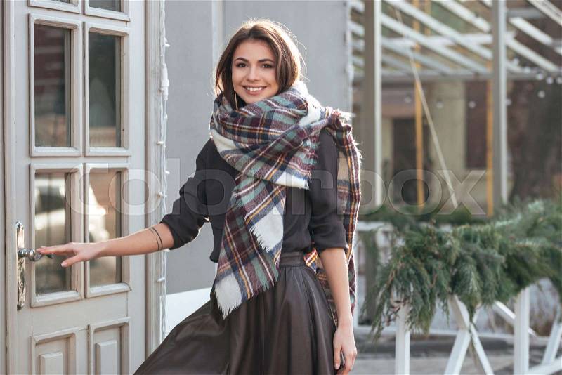 Picture of young happy lady looking at camera while walking near cafe outdoors, stock photo