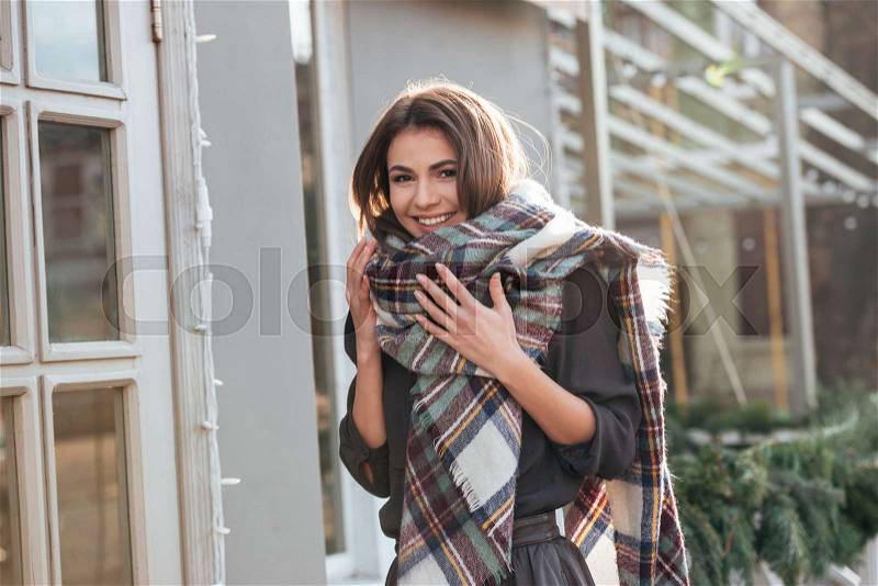 Picture of young happy lady looking at camera while walking near cafe outdoors, stock photo
