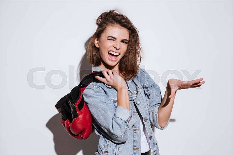 Picture of cheerful woman boxer dressed in jeans jacket and holding gloves isolated over white background, stock photo