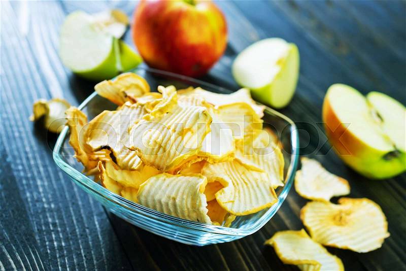Apple chips in bowl and on a table, stock photo