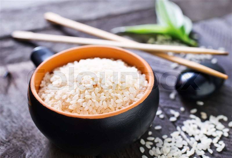 Raw rice in bowl and on a table, stock photo