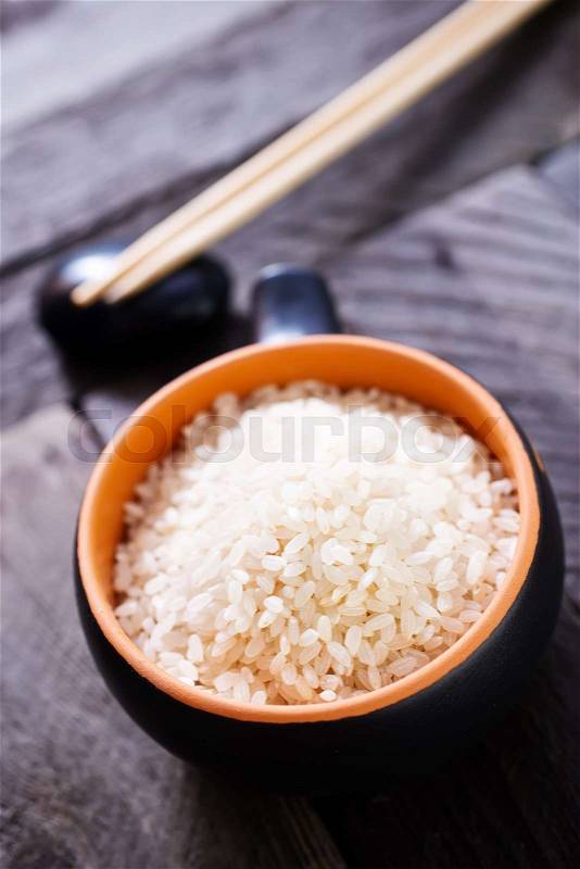 Raw rice in bowl and on a table, stock photo