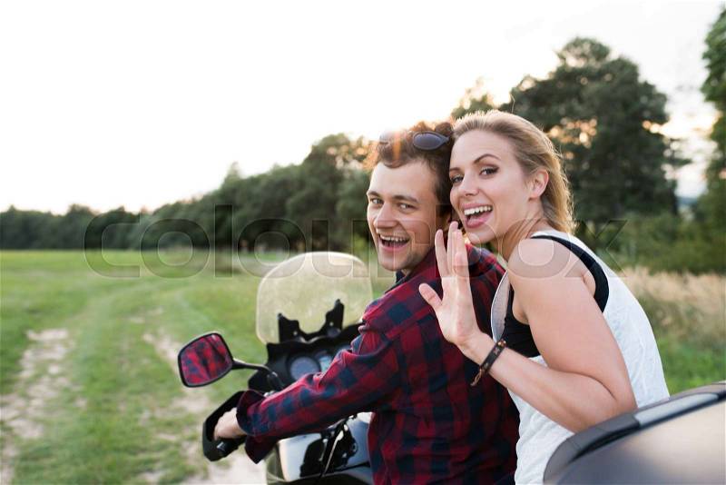 Beautiful young couple in love enjoying a motorbike ride in countryside, stock photo