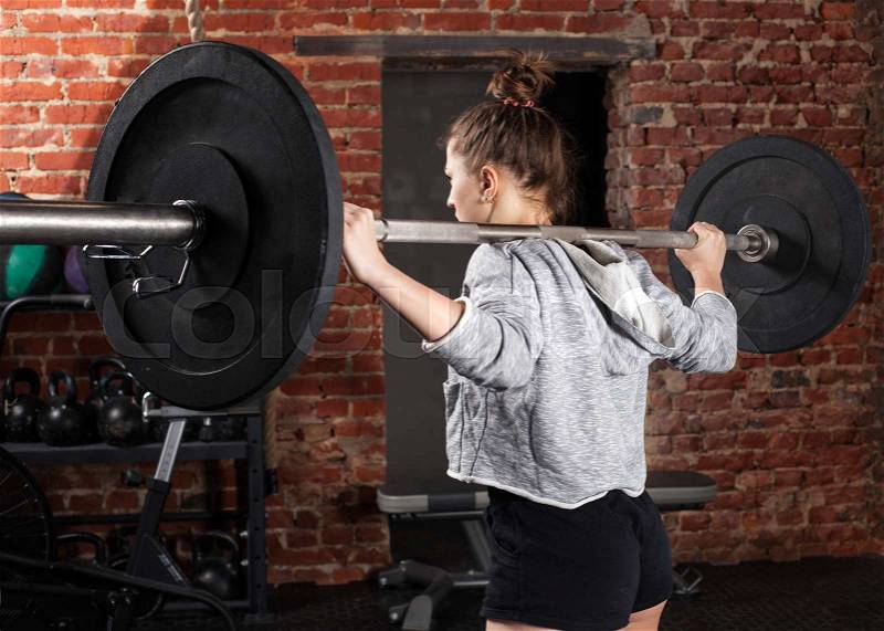 Woman athlete holding a barbell on his shoulders in the gym, stock photo