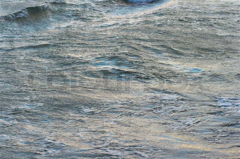 Evening sea waving surface with blue (sky) reflections and yellow (evening sun), stock photo