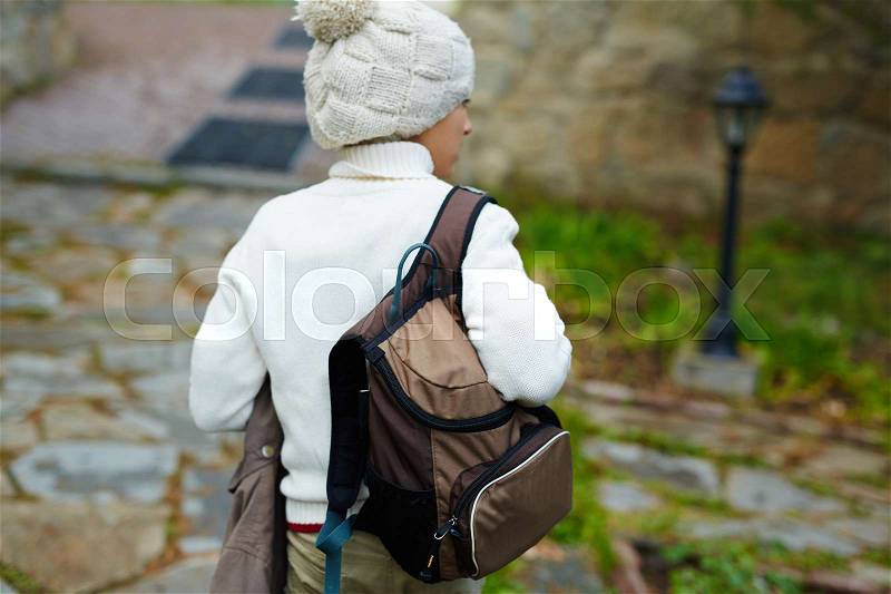 Youthful lad with satchel wearing knitted sweater and beanie hat, stock photo