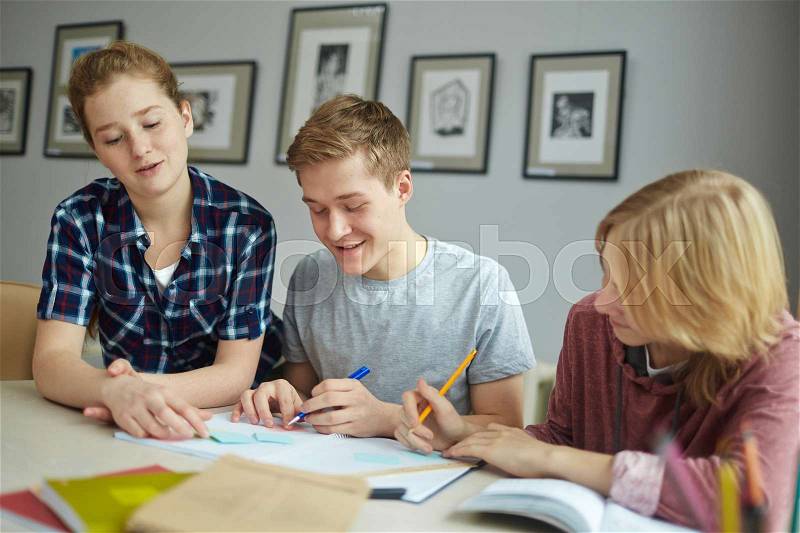 Friendly teens carrying out assignment in group, stock photo