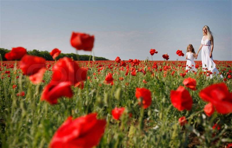 Mother and daughter on poppy field, stock photo