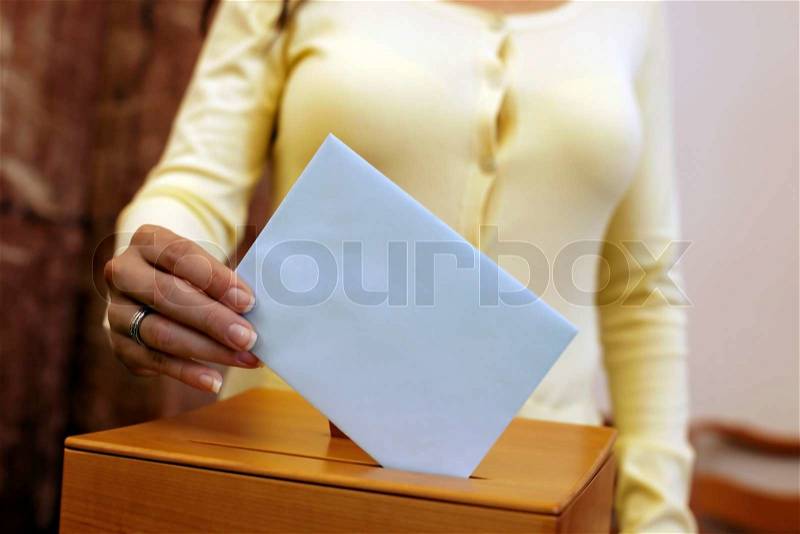 A young woman with a voter in the voting booth Voting in a democracy, stock photo