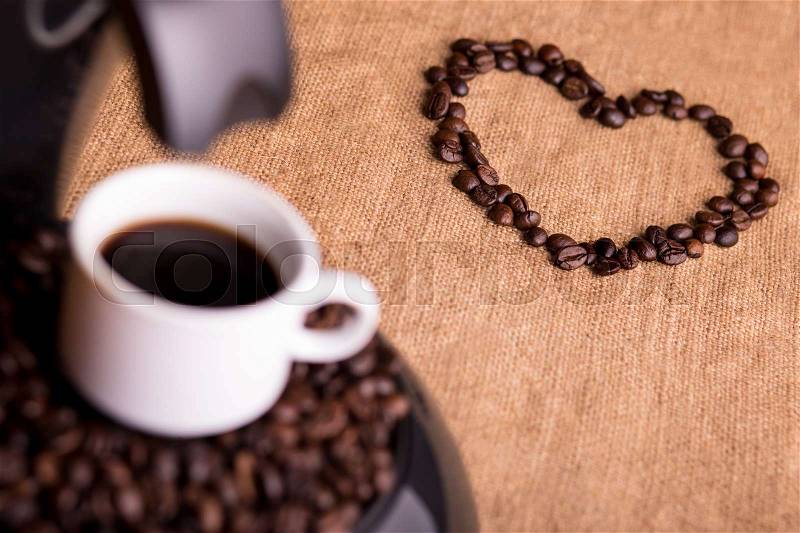 Cup of strong coffee on a coffee maker and heart made of coffee beans, stock photo