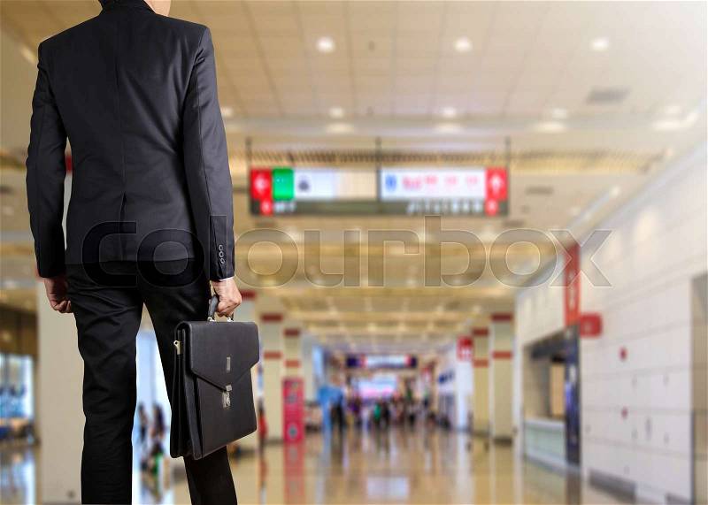 Businessman holding a briefcase in a modern office, stock photo