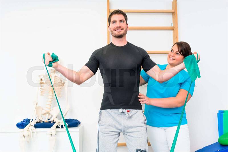 Young man exercising with resistance band in physical therapy, stock photo