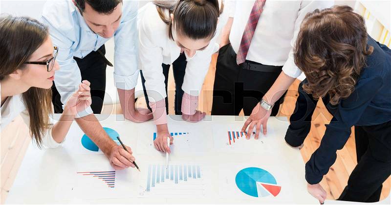 Financial consultants in bank analyzing data and discussing graphs, stock photo