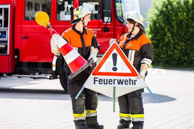 Female fire fighters in emergency operation setting up attention sign, stock photo