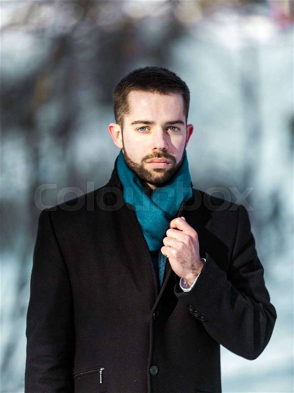 Portrait of young attractive beared man wears blue scarf in winter park, stock photo
