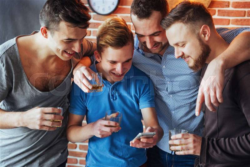 Cheerful old friends communicate with each other and phone watch, with glasses of whiskey in pub. Concept of entertainment and lifestyle. Wifi connected people in bar table meeting, stock photo