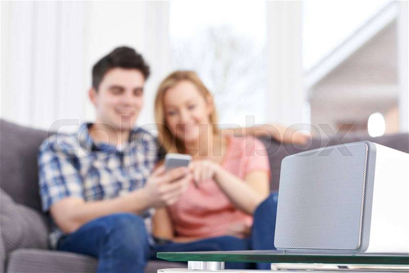 Couple Streaming Music From Mobile Phone To Wireless Speaker, stock photo