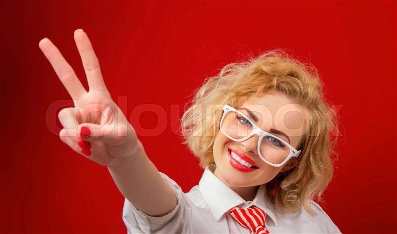 Smile young woman showing with fingers peace - sign ok, isolated on red, stock photo