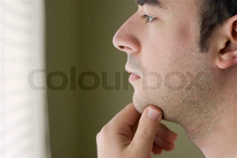 A young man with his hand on his chin thinking an important decision, stock photo