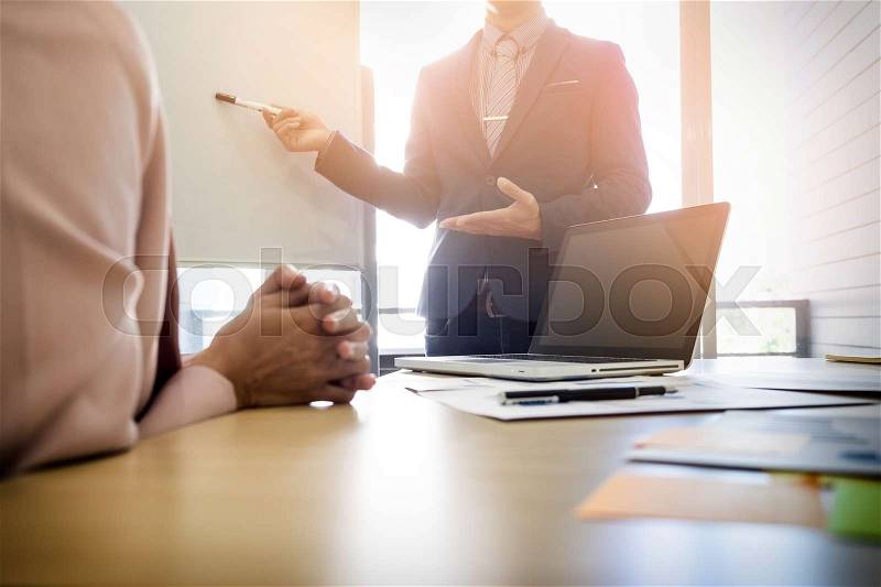 Businesswoman asking question during her colleagues presentation in bright office, stock photo